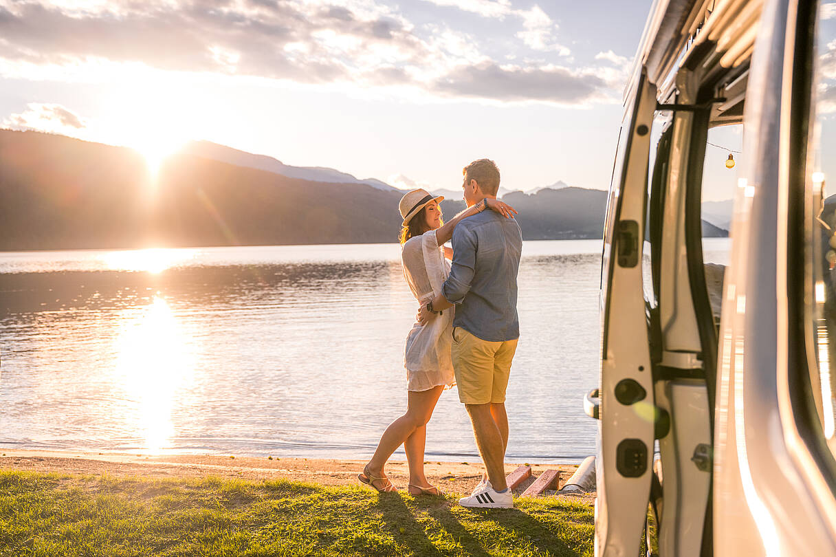 Pärchen genießt Sonnenuntergangn beim See beim Campen