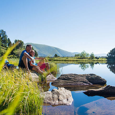 Pärchen sitzt in der Sonne am Ufer vom Windebensee auf der Nockalmstraße