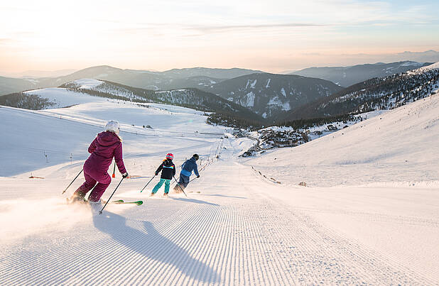 Familie fährt zusammen eine Piste am Falkert hinunter