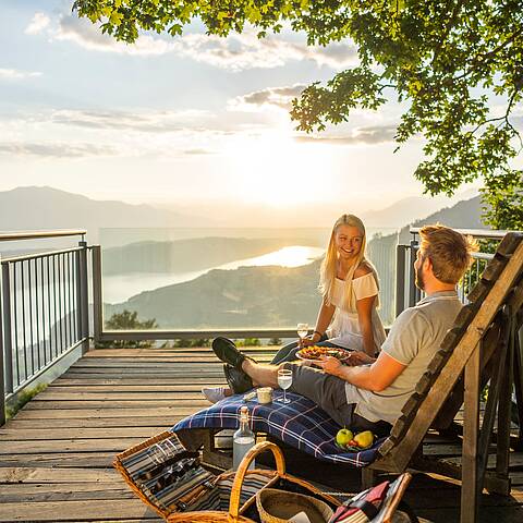 Pärchen genießt auf Bank mit einem Picknick am Sternenbalkon die Sonne