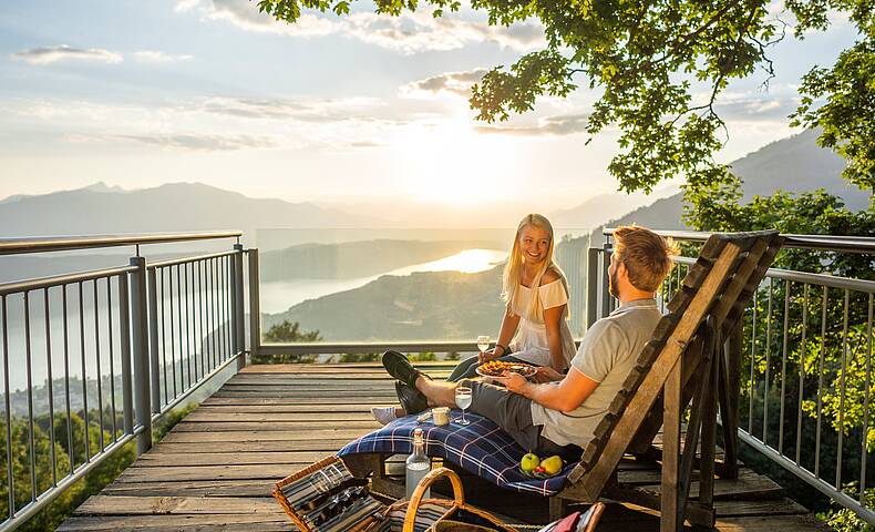Pärchen genießt auf Bank mit einem Picknick am Sternenbalkon die Sonne