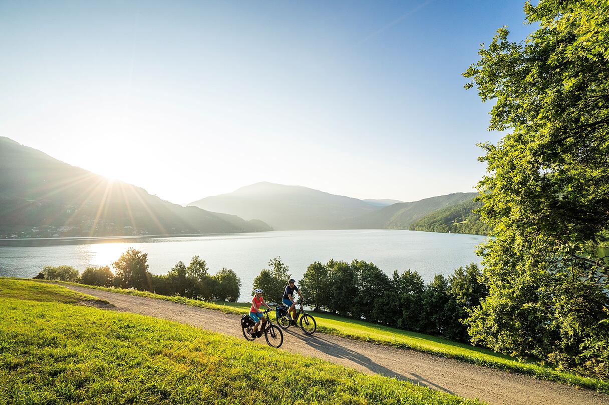 Mann und Frau fahren mit ihren Fahrrädern den Radweg am Millstätter See entlang
