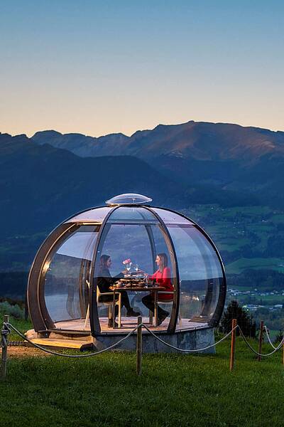 2 Personen genießen ihr Dinner in der Glaskuppel in einer Sommernacht