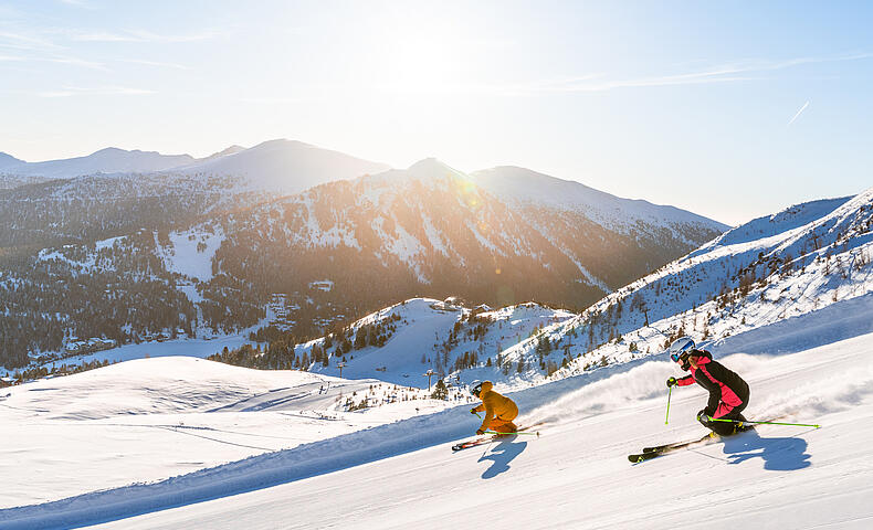 Skifahrer fahren die Piste auf der Turracher Höhe hinunter