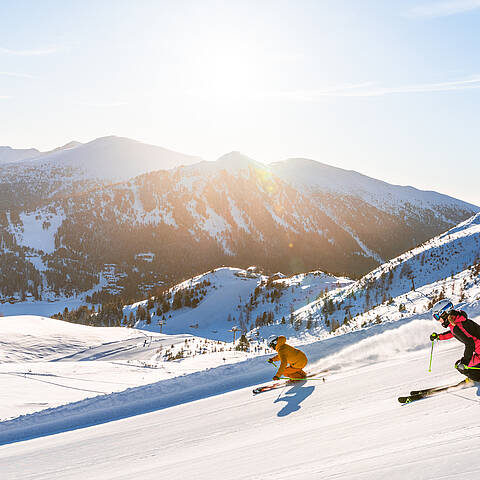 Skifahrer fahren die Piste auf der Turracher Höhe hinunter