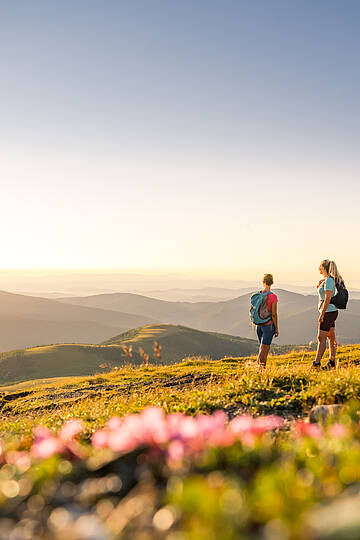 Zwei Wanderinnen auf Etappe 5 des Nockberge Trail oberhalb von Bad Kleinkirchheim mit Blick Richtung UNESCO Biosphärenpark.