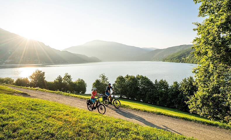 2 Personen fahren mit ihren Rädern den Radweg um den Millstätter See entlang